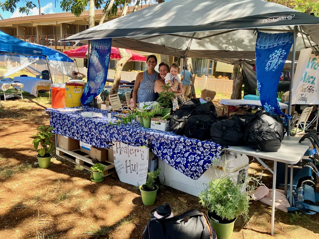 Kiʻi at a Healer's Hui community recovery hub, holding a child.
